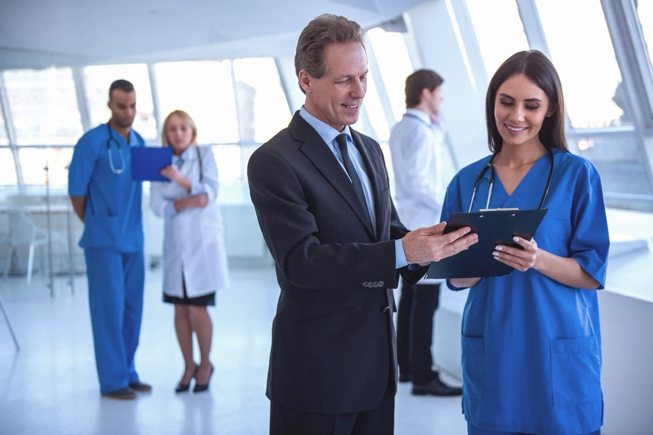 Handsome,Mature,Businessman,And,Beautiful,Young,Doctor,Are,Discussing,Documents Charge nurse briefing clinical staff on downtime response procedures at a hospital nurses station