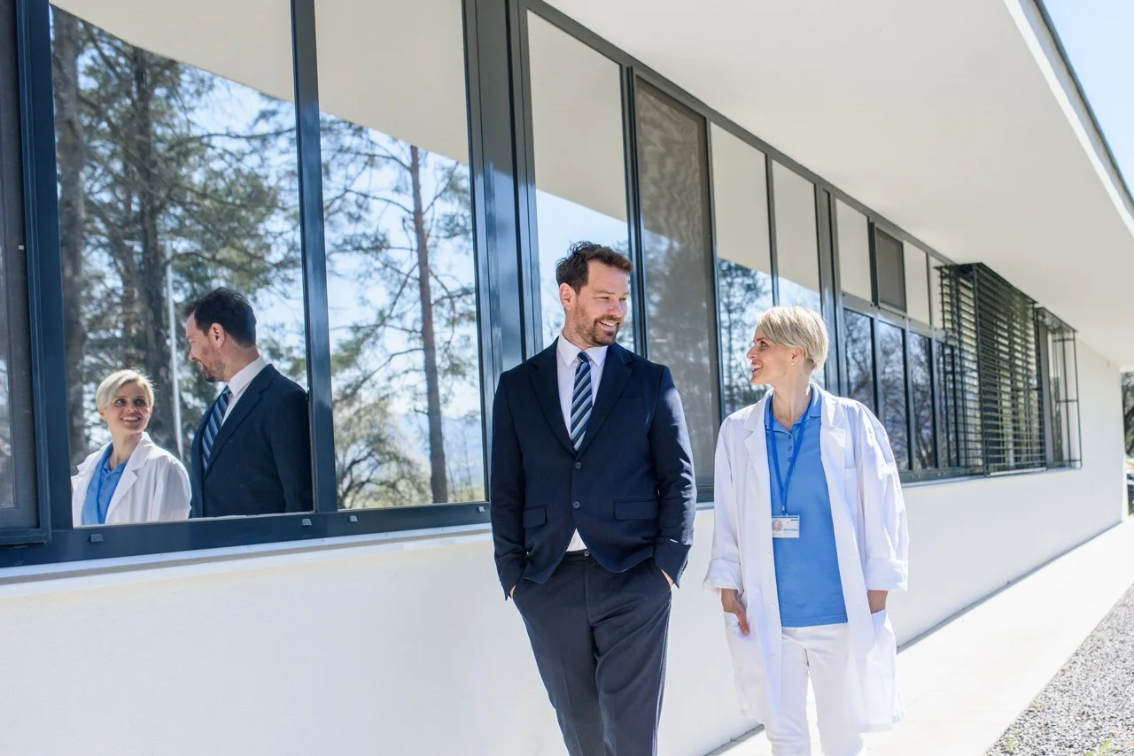 Doctor,And,Hospital,Administrator,Walking,Into,Hospital,,Talking. Respiratory therapist reviewing a ventilator patient's downtime records in an LTACH facility