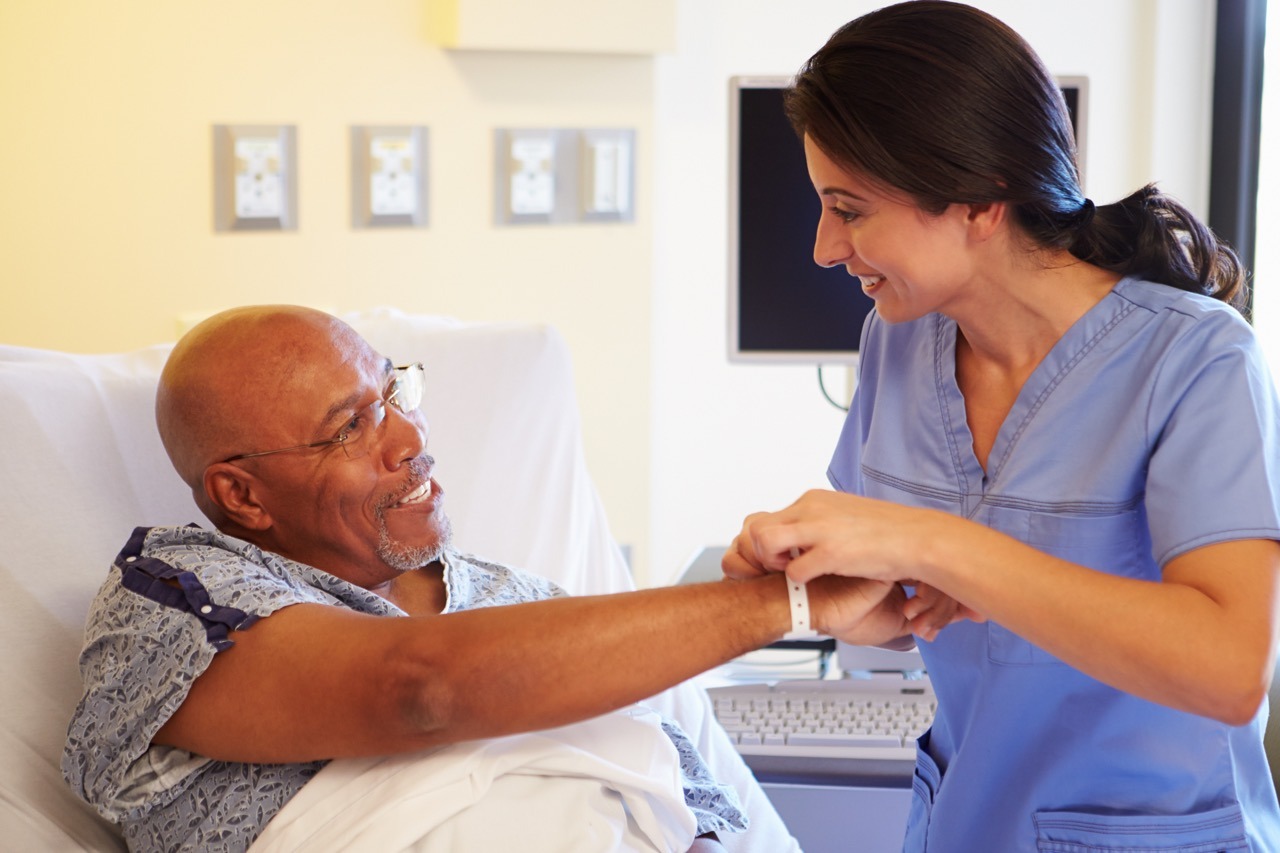 Nurse placing an identification wristband on a senior patient to protect patient identification during downtime