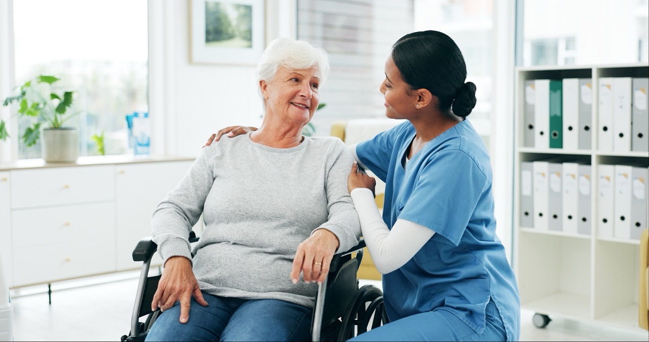 Nurse reassuring an older patient in a wheelchair, showing clear patient communication during an EHR outage