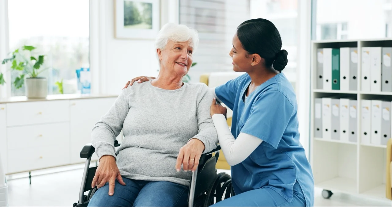 Nurse reassuring an older patient in a wheelchair, showing clear patient communication during an EHR outage