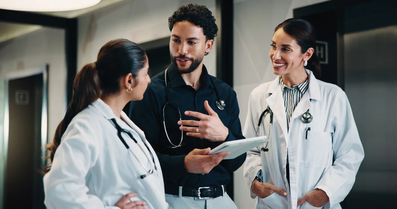 Medical,,Doctor,And,Group,With,Tablet,,Planning,Treatment,Or,Advice Physicians debriefing on a hospital downtime drill with results on a tablet